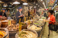 Shopper with basket considers purchase at local Japanese food stall, Nishiki Market (Kyoto's Kitchen), Downtown Kyoto, Japan