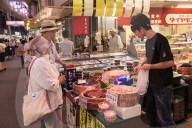 Shoppers make purchase at Omicho fresh food market, busy and colourful covered streets lined by stalls, Kanazawa, Japan