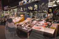 Diners sit and talk to seafood stall owner, Omicho fresh food market, network of covered stall lined streets, Kanazawa, Japan