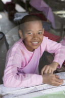 Buddhist novice schoolgirl sitting at her desk in the school classroom