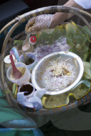 A snack seller offering stuffed banana leaf, onion and nut snacks on a train to Mandalay