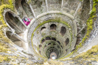 Photographer at the top of the spiral stairs inside the towers of Initiation Well at Quinta da Regaleira Sintra Portugal Europe