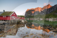 Fishing village and peaks reflected in water under midnight sun, Reine, Nordland county, Lofoten Islands, Arctic, Northern Norway, Scandinavia, Europe
