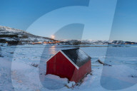 The blue light of dusk on the typical house of fishermen framed by the frozen sea Fjordbotn Senja Troms County Norway Europe