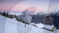 Pink sky at dawn above snow covered huts and trees Tagliate Di Sopra Gerola Valley Valtellina Orobie Alps Lombardy Italy Europe