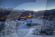 Lights of dusk illuminate the valley and the snow covered huts Tagliate Di Sopra Gerola Valley Valtellina Lombardy Italy Europe