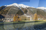 Autumn colors frame the village of Zernez surrounded by woods and snowy peaks Engadine Canton of GraubÃ¼nden Switzerland Europe