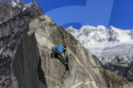 Climber on steep rock face in the background blue sky and snowy peaks of the alps Masino Valley Valtellina Lombardy Italy Europe