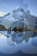 Hikers on the shores of Lac de Cheserys  where Aiguille Verte is reflected at dawn Chamonix Haute Savoie France Europe