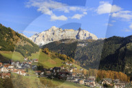 The colorful woods frame the village and the high peaks in autumn Gardena Pass South Tyrol Trentino Alto Adige Italy Europe
