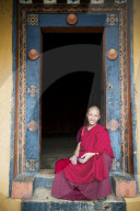 Young monk sitting in an ornate doorway