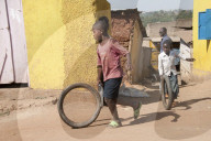 Namuwongo slum area, Kampala, where VHTs (village health team) do TB outreach work - boy running with bike tyre