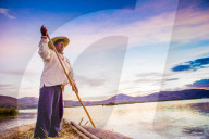 Quechua Man rowing a boat on the Floating Grass islands of Uros, Lake Titicaca, Peru