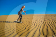 Woman sand boarding on sand dune, Huacachina Oasis, Peru