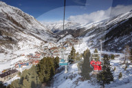 Looking down on the village of Obergurgl sat at the top of the Otztal valley as skiers ascend the mountain on chairlifts, Tyrol, Austrian Alps, Austria, Europe