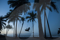 A girl plays on a swing tied between palm trees on the Carribean coast at Palomino in Colombia