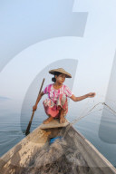 A young woman pulls in her nets at the end of the day on Indawgyi Lake, Kachin State, Myanmar (Burma), Asia