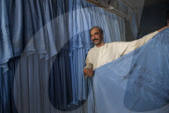 A shopkeeper in Herat in Afghanistan demonstrates that not all Burqas are identical - subtle differences in embroidery help iden