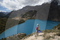 A trekker stands above the turquoise blue Phoksundo Lake in the Dolpa region, Himalayas, Nepal, Asia