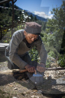 A Tamang man in the Tamang heritage region of Nepal close to Langtang sharpens an axe in the traditional method using a piece of