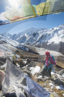 A woman trekking in the Langtang valley in Nepal stands on the top of Kyanjin Ri and looks out towards Ganchempo in the in the d