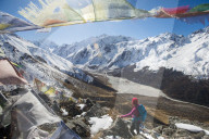 A woman trekking in the Langtang valley in Nepal stands on the top of Kyanjin Ri and looks out towards Ganchempo in the in the d