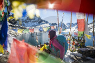 A trekker stands among prayer flags beside the holy lakes at Gosainkund in the Langtang region of Nepal