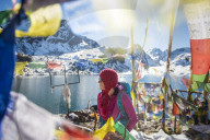 A trekker stands among prayer flags beside the holy lakes at Gosainkund in the Langtang region of Nepal