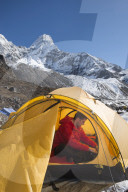 A mountaineer in Nepal packs his bag in preparation to climb Ama Dablam, the 6,856m peak in the distance.