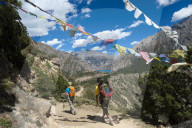 Prayer flags mark a high point in the trail where trekkers are rewarded with their first glimpse of Phoksundo lake in Nepal