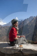 A trekker stops on the trail for some fuel, Ama Dablam is the peak visible in the distance