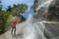 A man pauses to smile for the camera while canyoning in a waterfall in Nepal