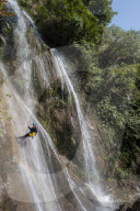 A girl pauses to smile for the camera while canyoning in a waterfall in Nepal
