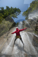 A man pauses to hold his arms in the falling water while canyoning in Nepal