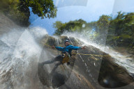 A man pauses to smile for the camera while canyoning in a waterfall in Nepal