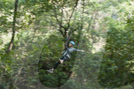 A girl holds her arms out and on a zip line in Nepal