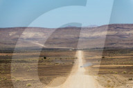 A 4x4 car leaves a cloud of dust as it apporachs along the long dusty road to the Fish River Canyon, Namibia, Africa