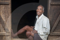 An old farmer sits in the doorway of his house in India