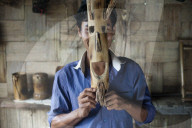 A young man holds a mask made from bamboo to his face