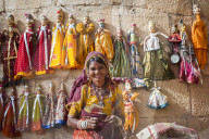 A woman sells puppets along the fort walls in Jaisalmer in the desert state of Rajasthan, India, Asia