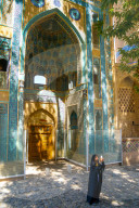 Young Iranian girl in chador taking picture in front of Jameh Mosque, Natanz, Iran