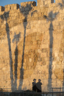 Two Orthodox Jewsh with palm tree shadows in background along the Old City walls. Jerusalem Old City. Israel.