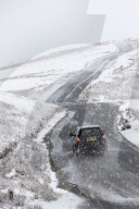 A car negotiates a road through a wintry landscape in the Elan Valley area in Powys, Wales, UK.