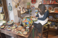 A craftswoman hand painting traditional ceramics, Erice, Sicily, Italy