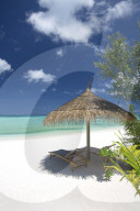 lounge chairs under shade of umbrella on tropical beach, maldives