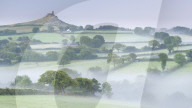 Rolling mist covered countryside surrounding Brentor Church, Dartmoor, Devon, England. Summer (August) 2015.