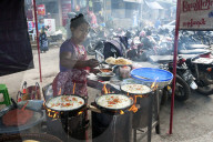 Woman frying rice pancakes with fillings on a street market fast food stall in Pyin Oo Lwyn, Mandalay Division, Myanmar.