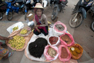 Woman in straw hat selling lemons, tea and spices on a blanket outside Kalaw market, Shan state, Myanmar