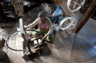 Woman spinning silk thread on a spinning wheel with bicycle wheel, Ko Than hlaing Weaving,  Inpawkhan, Inle Lake, Shan state.