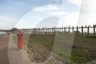 Orange robed monk photographing people crossing U Bein's Bridge, supported by 984 teak posts over Thaumthaman Lake, Mandalay.